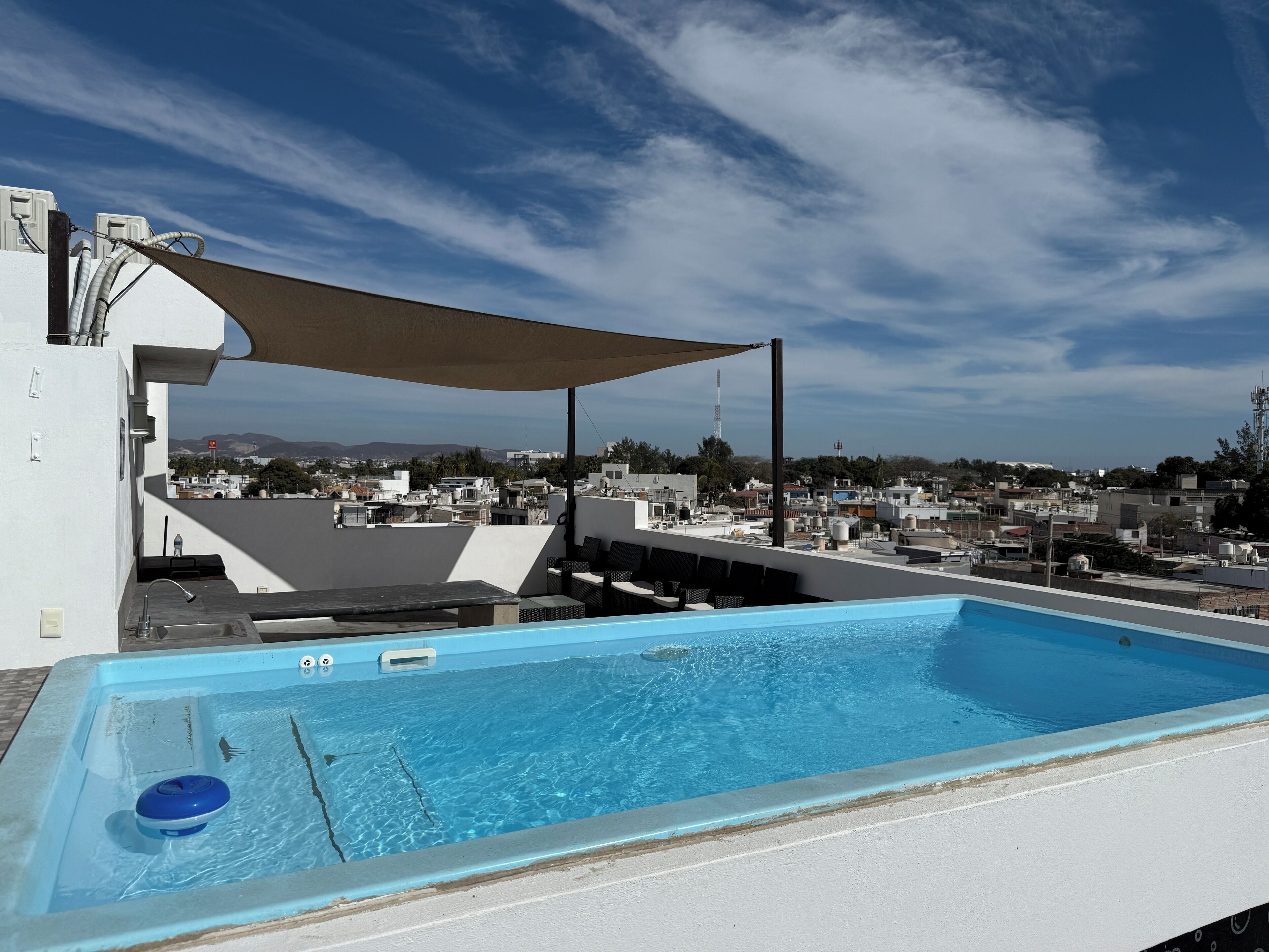 A rooftop pool with a view of the cityscape, including buildings and mountains in the distance.
