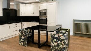 Et moderne køkken med hvide skabe, en sort bordplade og en central ø med blomstret betræk.