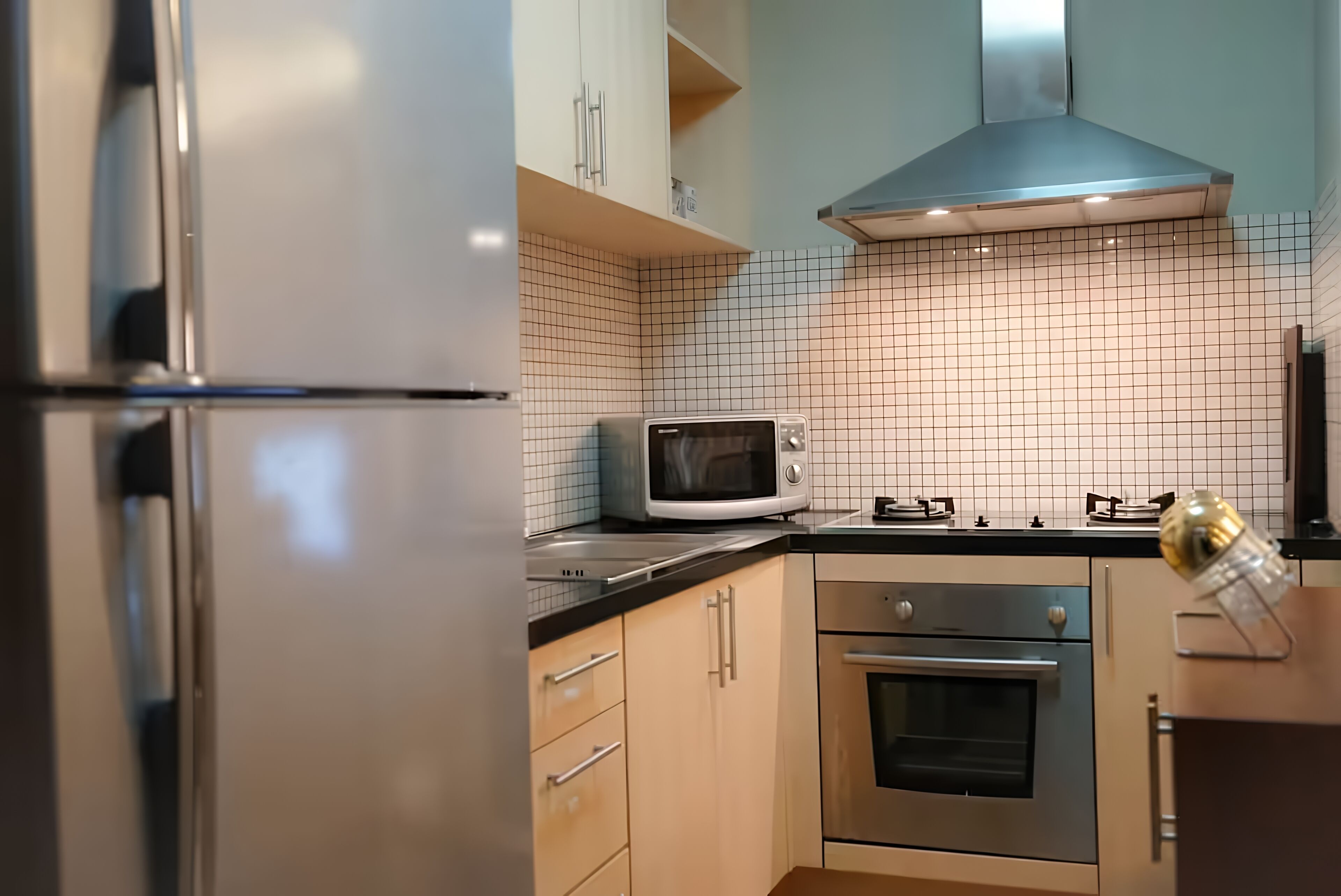 A kitchen with a stainless steel refrigerator, a microwave, a gas stove, and a built-in oven.
