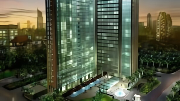 A modern high-rise building with a glass facade, surrounded by greenery and other buildings.