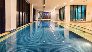 A long indoor swimming pool with tiled walls and a clear glass bottom.