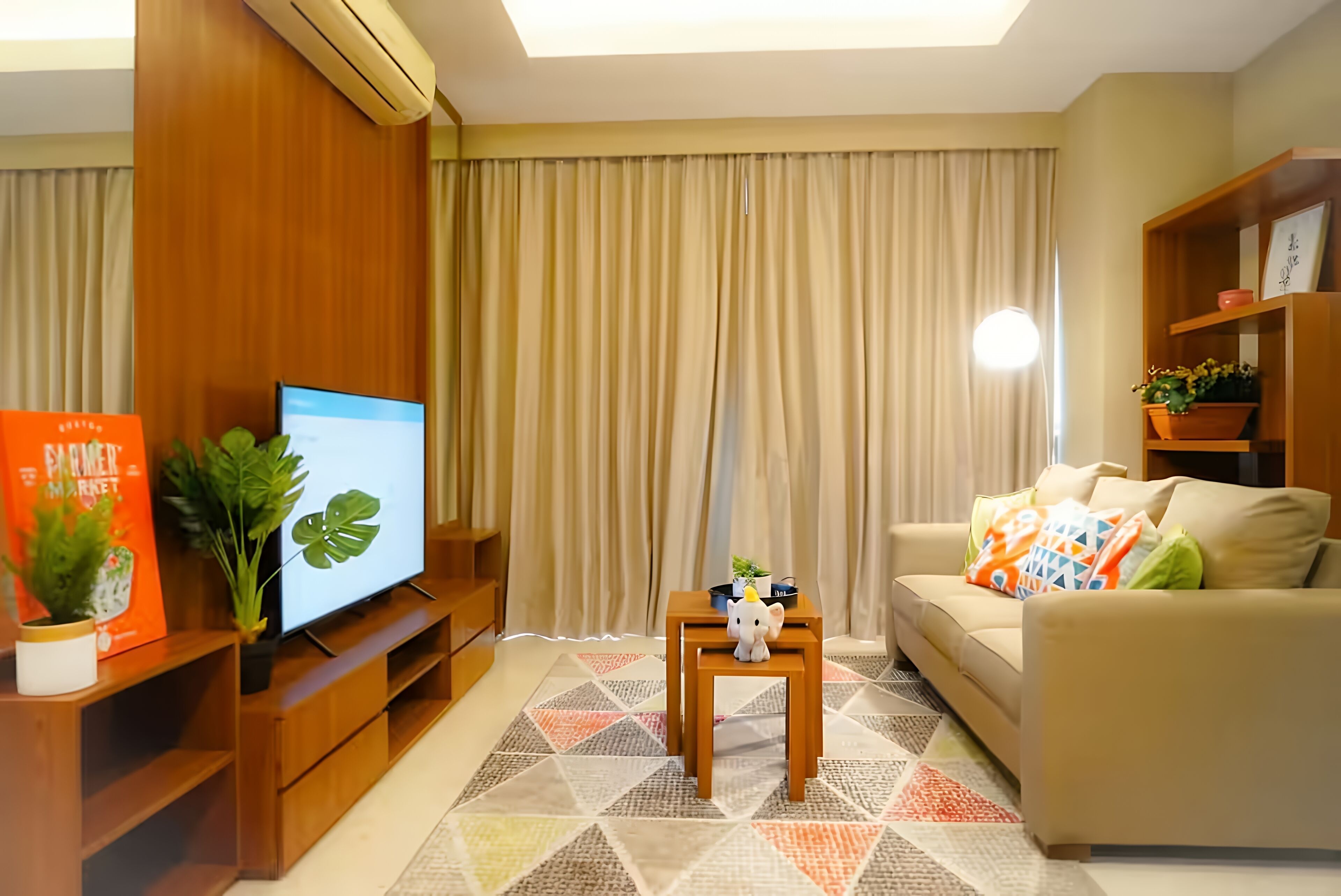 A living room with a TV, wooden entertainment unit, sofa, and a small table with a plant.