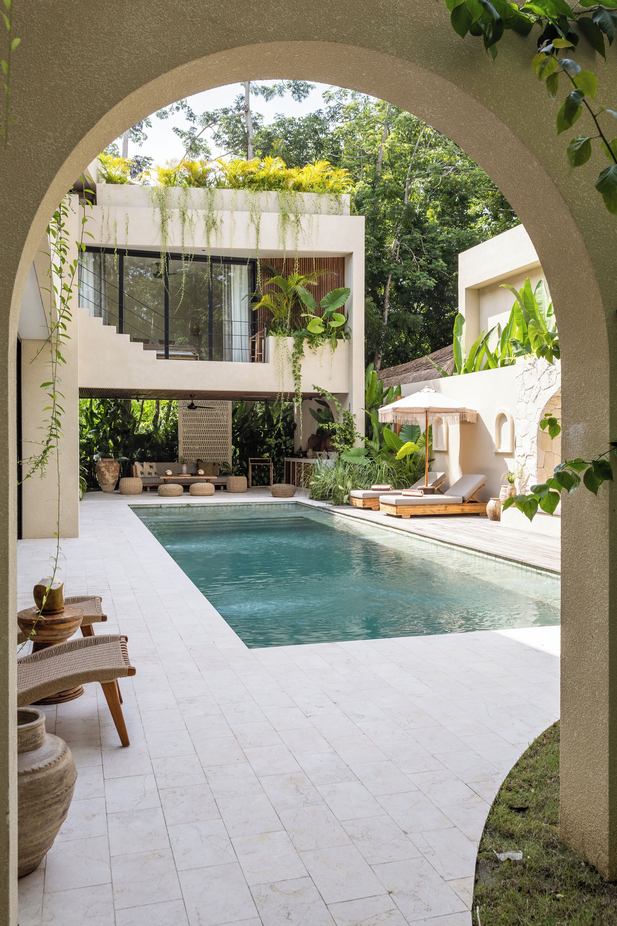 A modern pool area with a clear view of the pool, lounge chairs, and a seating area with a table and chairs.