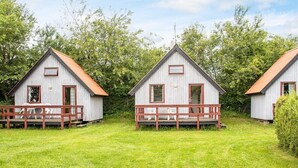 Three wooden cabins with red-framed windows and doors, each with a small porch and a metal roof. - 6 Person Holiday Park Home in Grindsted (Grindsted)
