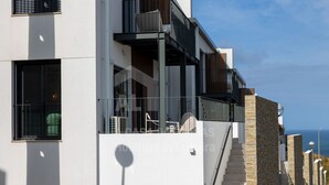 A modern building with a balcony, large windows, and a staircase leading to an upper level. - Casa Brisa by Acasadascasas (Mafra)