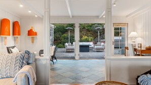 A room with a sofa, a dining table, and a view of an outdoor patio area. - Coastal Elegance by the Shore (La Jolla)