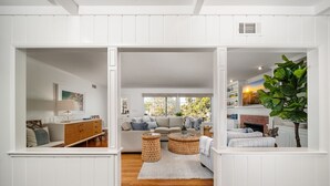 A spacious living area with a sofa, two round wicker side tables, a fireplace, and a large plant. - Coastal Elegance by the Shore (La Jolla)
