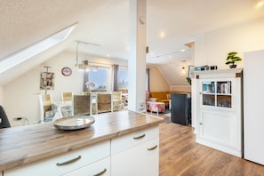 Eine moderne Küche mit Holzarbeitsplatte, weißen Schränken und einem Essbereich mit Tisch und Stühlen.