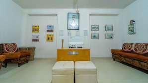 A reception area with a reception desk, two sofas, a small table, and framed pictures on the walls. - Hotel Hinduja Luxury Camp & Resort (Osian)