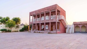 A multi-story building with a balcony, a staircase, and a paved courtyard. - Hotel Hinduja Luxury Camp & Resort (Osian)