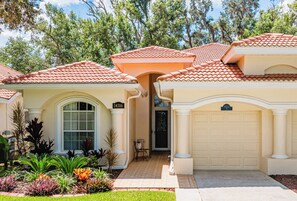 A residential house with a beige exterior, red-tiled roof, and a well-maintained garden.