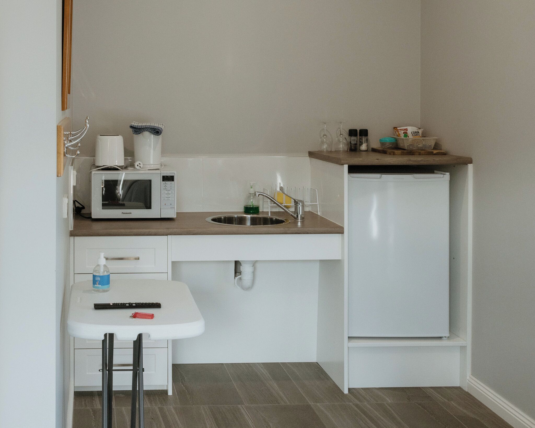 Una kitchenette compacta equipada con microondas, pileta y heladera pequeña.