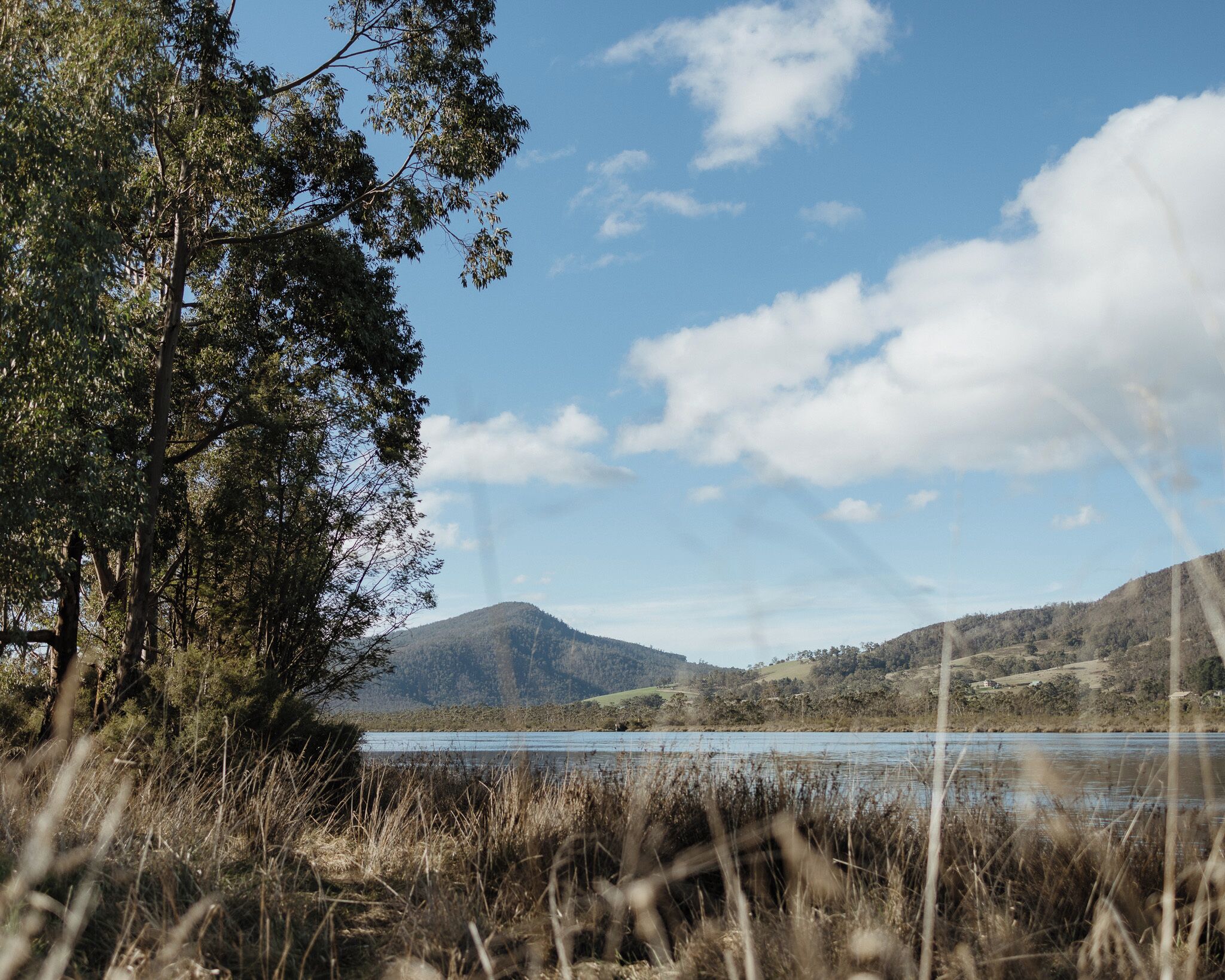 A natural landscape with a lake, hills, and trees.