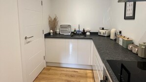 A compact kitchen with white cabinets, a black countertop, and a wooden floor. - Premium apartment close to the beach, Turner contemporary and dreamland Pets ok. (Margate)