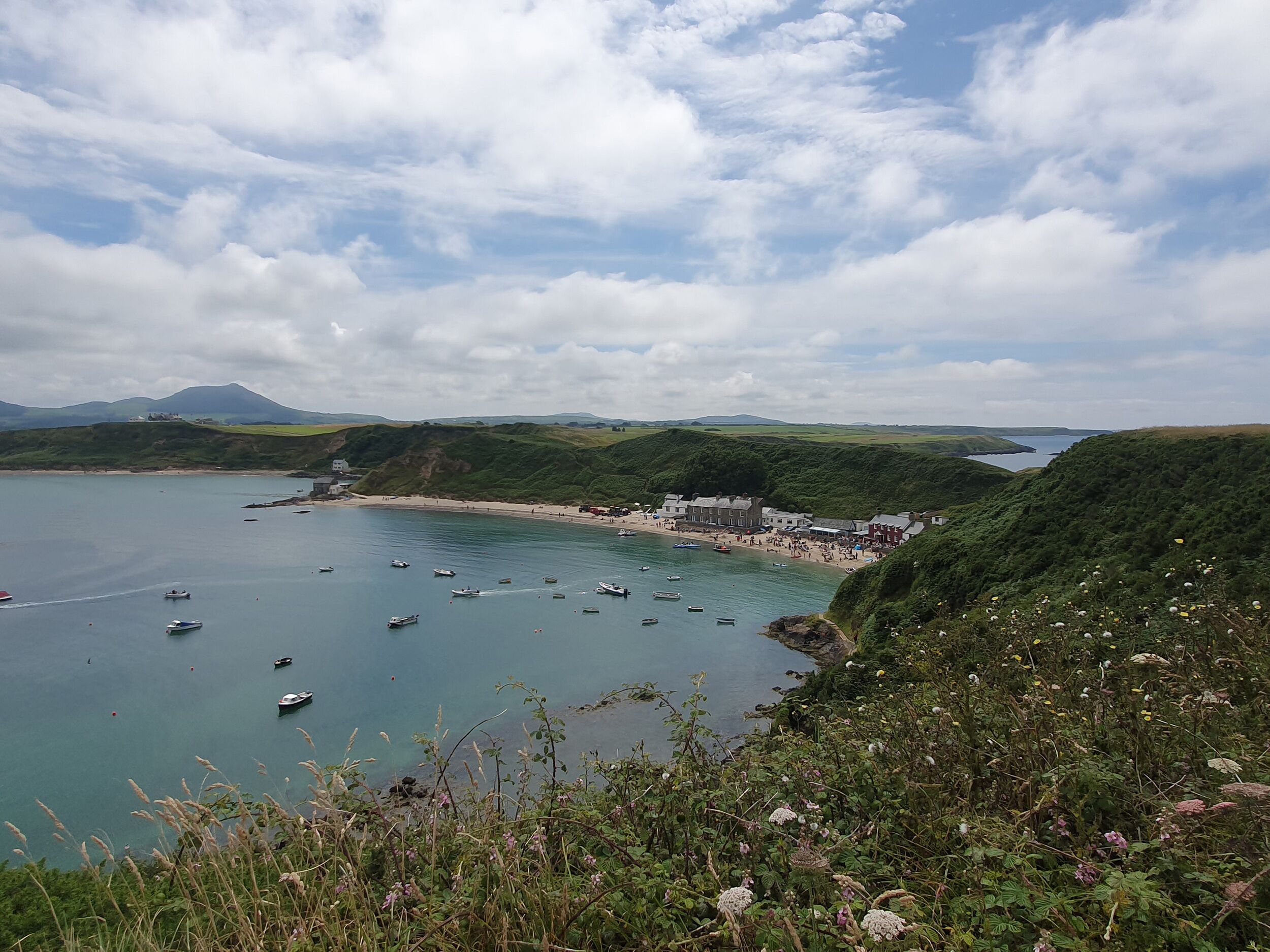 A coastal town with boats on the water, a beach, and buildings along the shore.