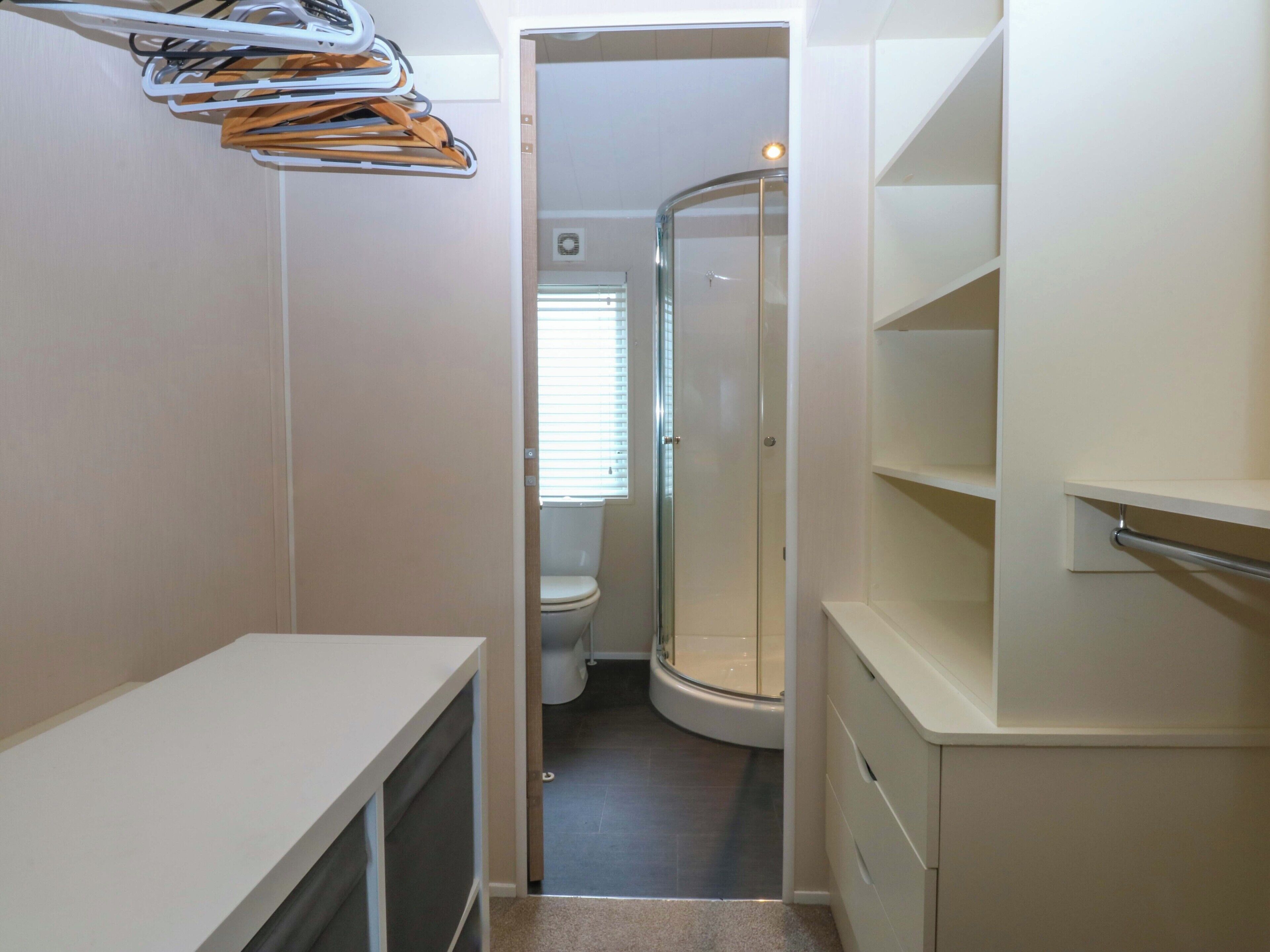 Une salle de bain compacte comprenant une douche, des toilettes et des rangements intégrés.