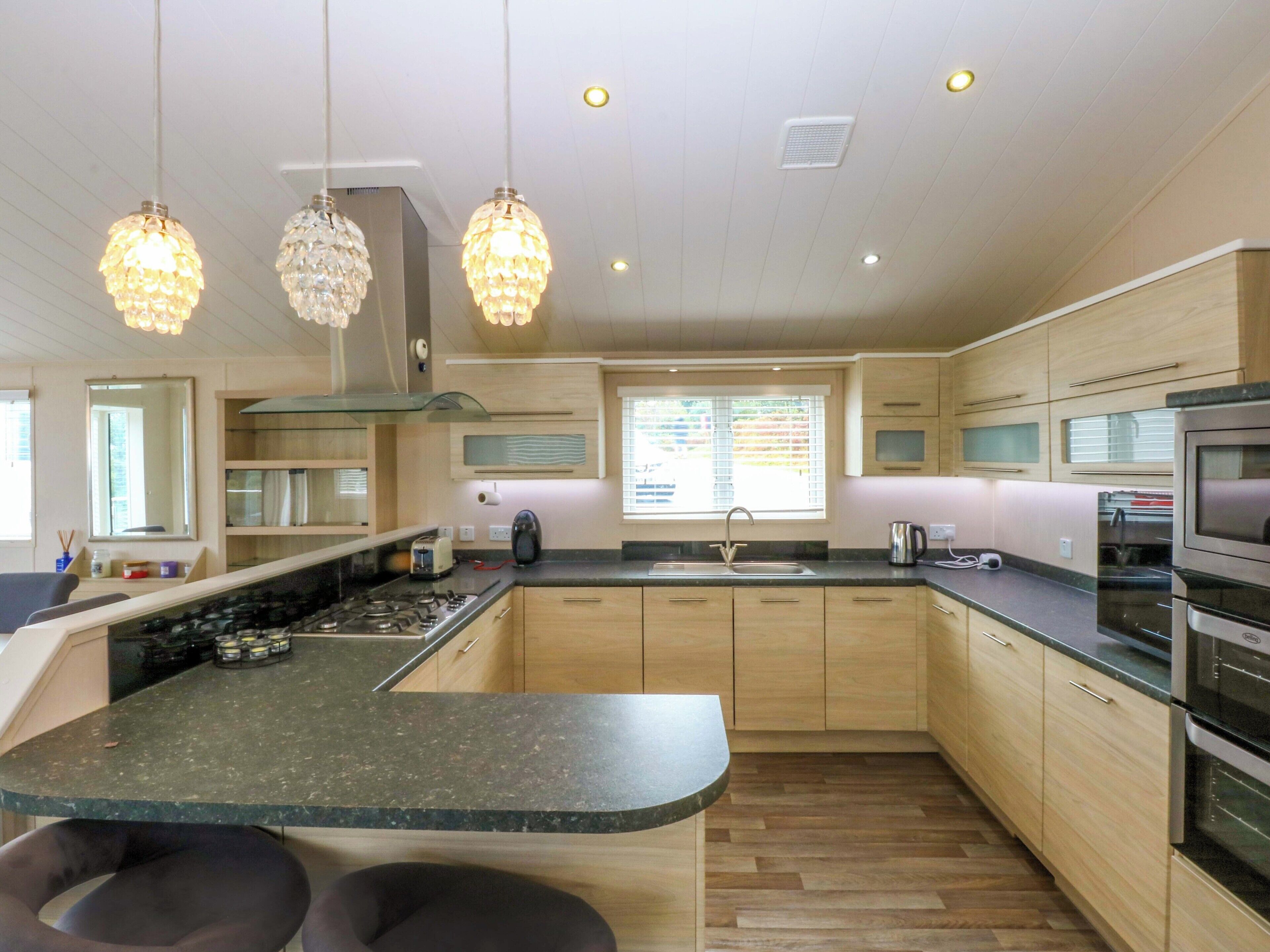 Una cocina moderna con una isla central, armarios de madera, electrodomésticos de acero inoxidable e iluminación colgante.