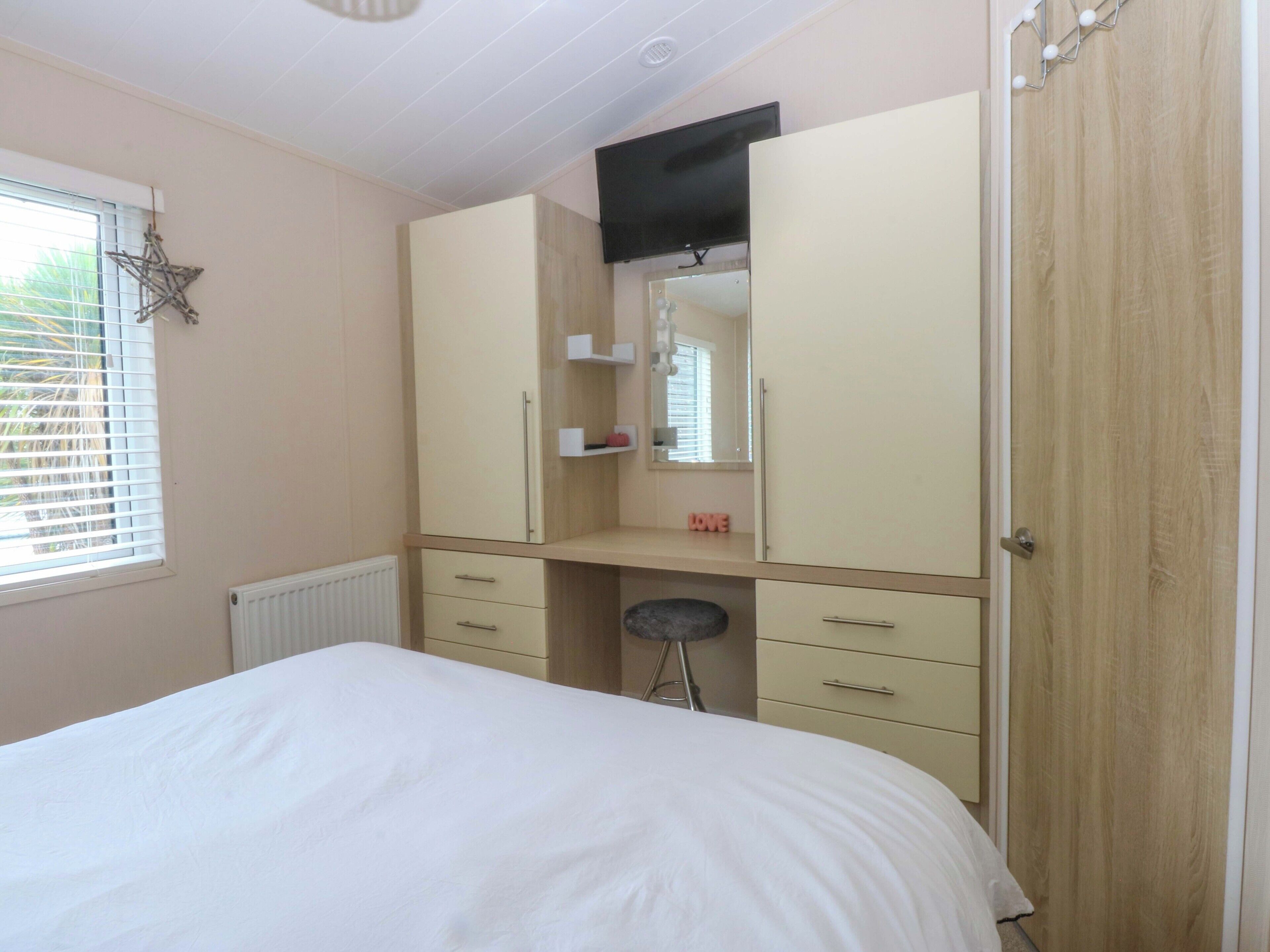 Un dormitorio con cama, armario, espejo y radiador.