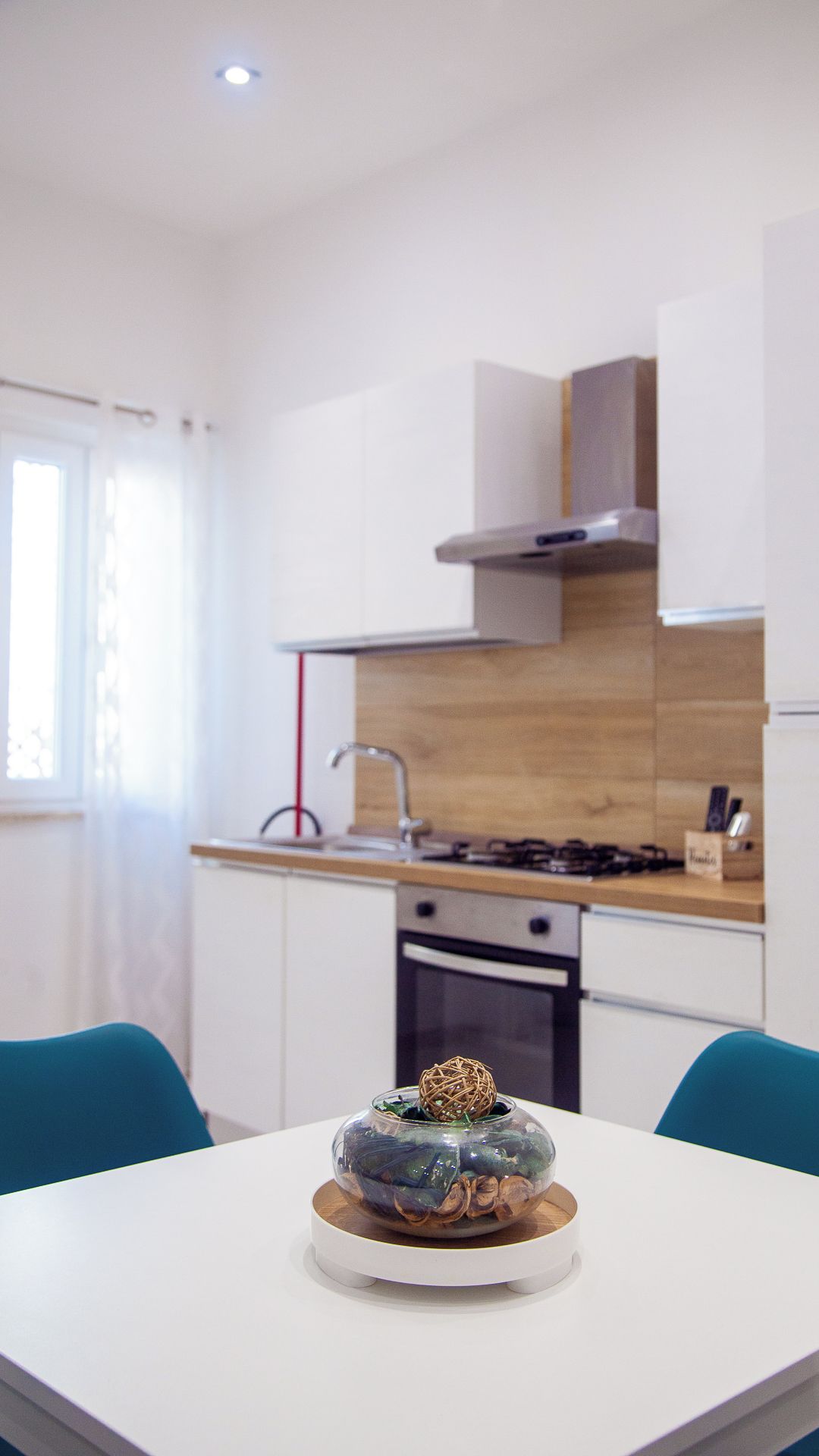 Une cuisine moderne avec des meubles blancs, un plan de travail en bois et une cuisinière à gaz.