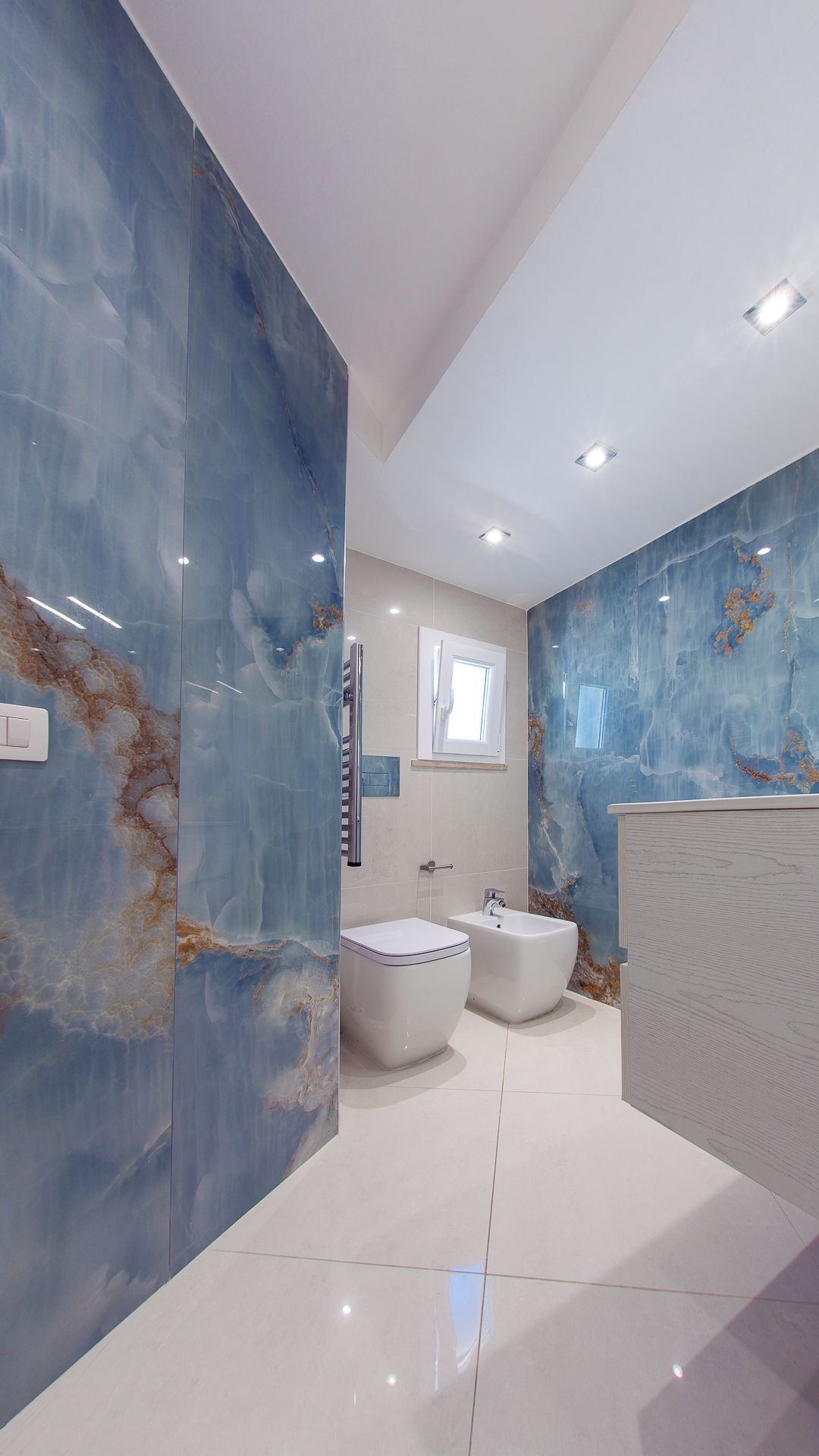 Un baño moderno con un espejo grande, un bidé y un inodoro.