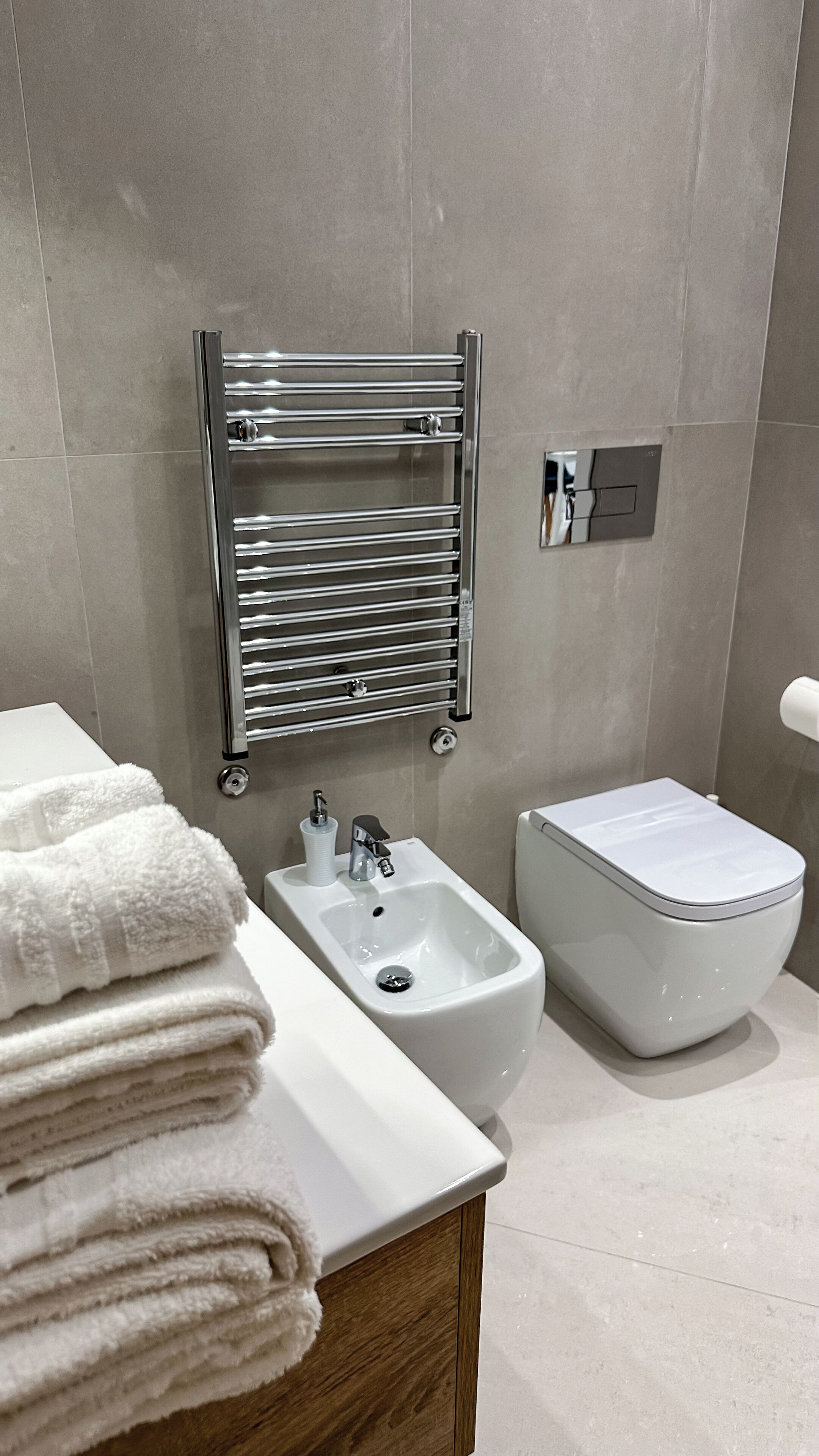 A modern bathroom with a white sink, bidet, and toilet.