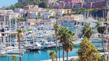 A marina with numerous boats docked, a gas station, and a view of historic buildings in the background.
