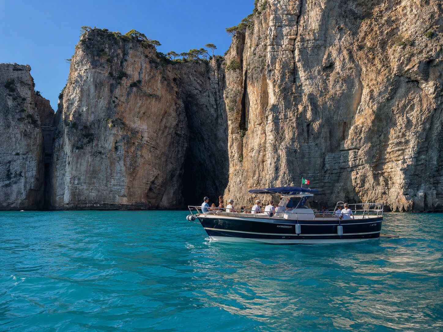 Un barco con pasajeros en un mar turquesa, rodeado de acantilados rocosos.