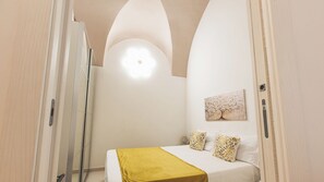 Een slaapkamer met een bed, een schilderij en een gele plaid.
