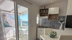Una cocina moderna con vista al mar, un comedor con mesa y sillas, y un balcón con vista a la costa.