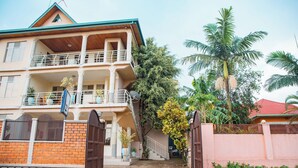 A two-story house with a balcony, a gated entrance, and a palm tree in the background. - Fanad Hotel (Gisenyi)