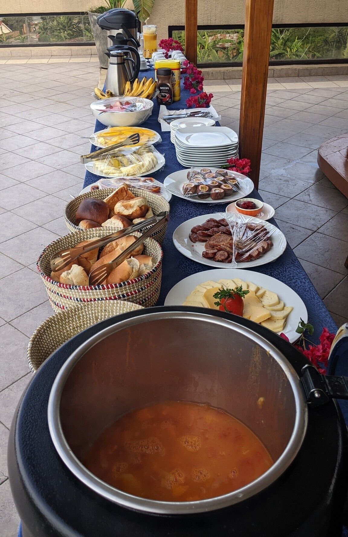 Une table de buffet garnie de divers plats et un grand pot de soupe.