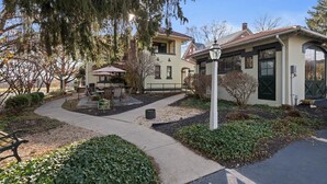 Ein Gebäude mit einer Terrasse, Sitzgelegenheiten im Freien und einer Lampe.