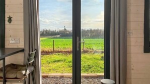 A room with a sliding glass door leading to a green field. - Barn Owl Cabin at Redroofs - Pet Friendly! (Forfar)