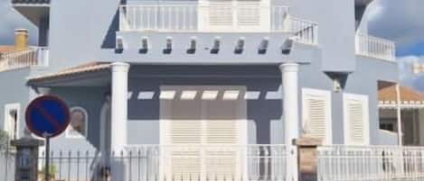 A large, light blue house with a balcony and a garage.