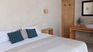 A bedroom with a bed, bedside tables, a wooden bench, a sink, and a mirror. - Dona Ana Guesthouse (Lagos)