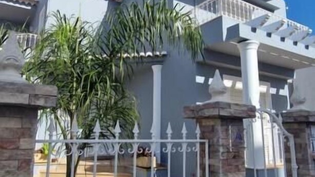 A modern house with a white exterior, a tiled roof, and a white fence with decorative elements. - Dona Ana Guesthouse (Lagos)