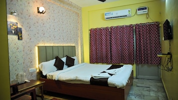 Un dormitorio con cama, mesita de noche, aire acondicionado de pared y cortinas estampadas.