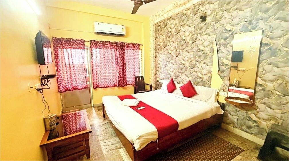 A bedroom with a bed, a TV, a mirror, and a stone wall.