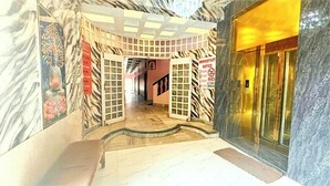 Un pasillo con diseño de pared a rayas de cebra, un ascensor de vidrio y un letrero que indica prohibido fumar.