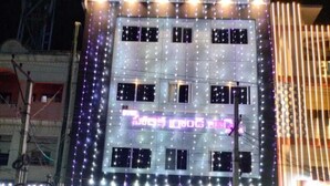 A multi-story building with a prominent SBI bank sign, multiple windows, and a series of lights on the facade.