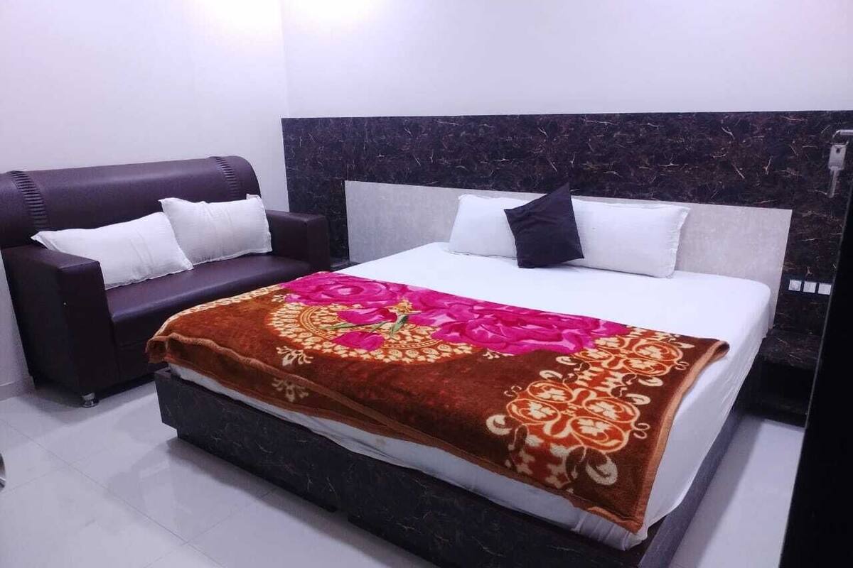 Een slaapkamer met een bed, een donkere bank en een hoofdbord met een marmerachtige textuur.