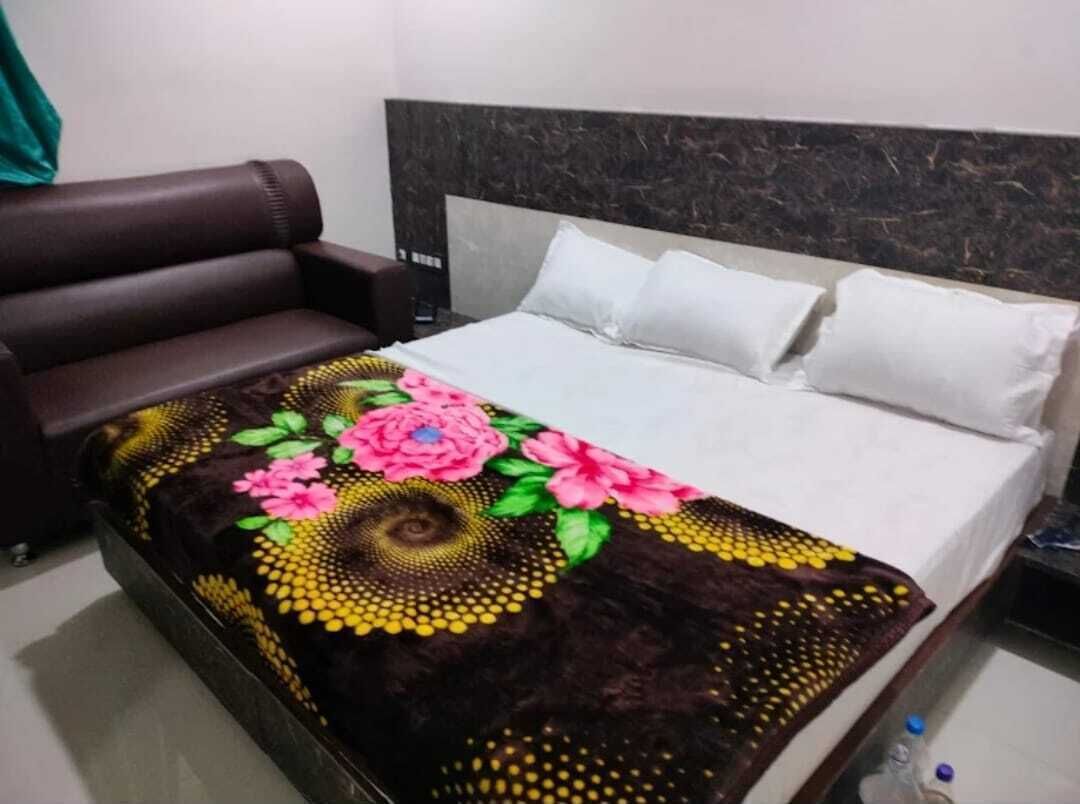 A bed with a floral bedspread, a dark headboard, and white pillows.