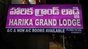 A sign for Harika Grand Lodge advertising A/C and non-A/C rooms with contact numbers.