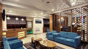 A lobby with blue sofas, a coffee table, a reception desk, and a decorative partition. - Cilantro Unwind Delisso Abode (Gangtok)