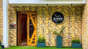 A hotel entrance with a stone facade, a wooden door, and a sign reading "CILANTRO UNWIND THE DELISSO ABODE". - Cilantro Unwind Delisso Abode (Gangtok)