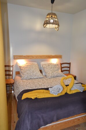 A neatly made bed with patterned bedding, a wooden headboard, and a hanging light fixture.
