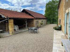 A courtyard with stone buildings, a gravel path, and outdoor seating.