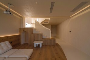 A modern interior with a wooden floor, a white sofa, a small round table, and a staircase with a unique design. - Baimanchuan  hotel (Deyang)