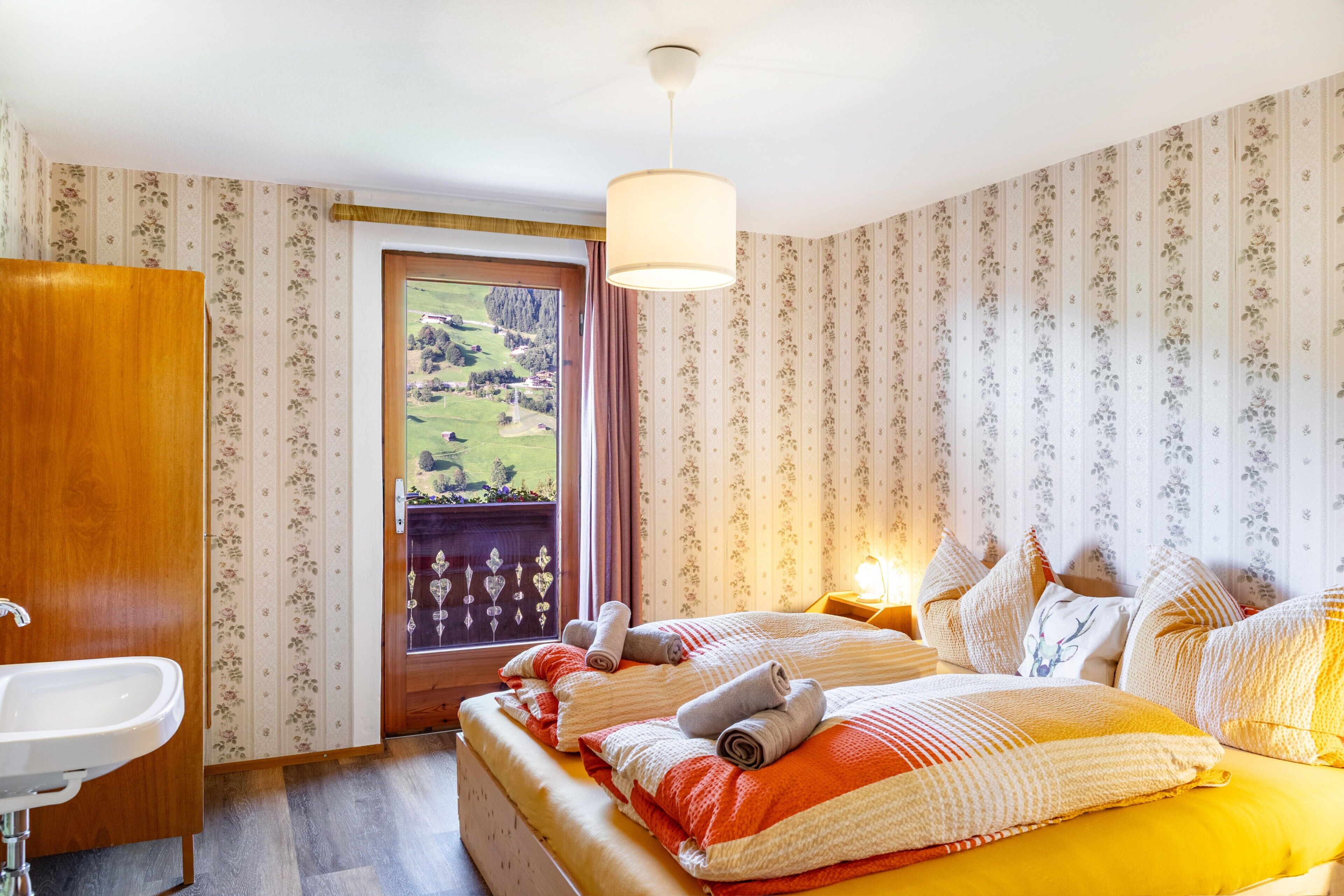 A bedroom with a bed, a bedside table, a window with a view, and a door.