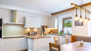 A modern kitchen with white cabinets, a wooden island, and a dining area with a table and chairs.